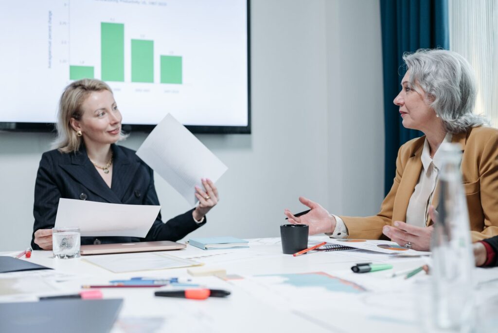 Dos directivas conversan sobre unos gráficos en una reunión