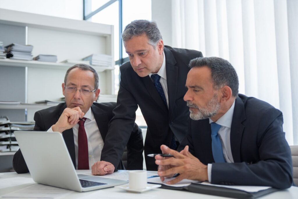 Tres directivos revisan un plan en un portátil