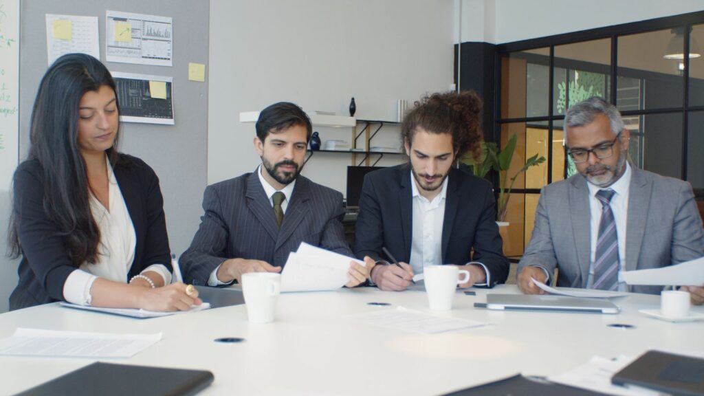 Un equipo de profesionales trabaja con documentos alrededor de una mesa